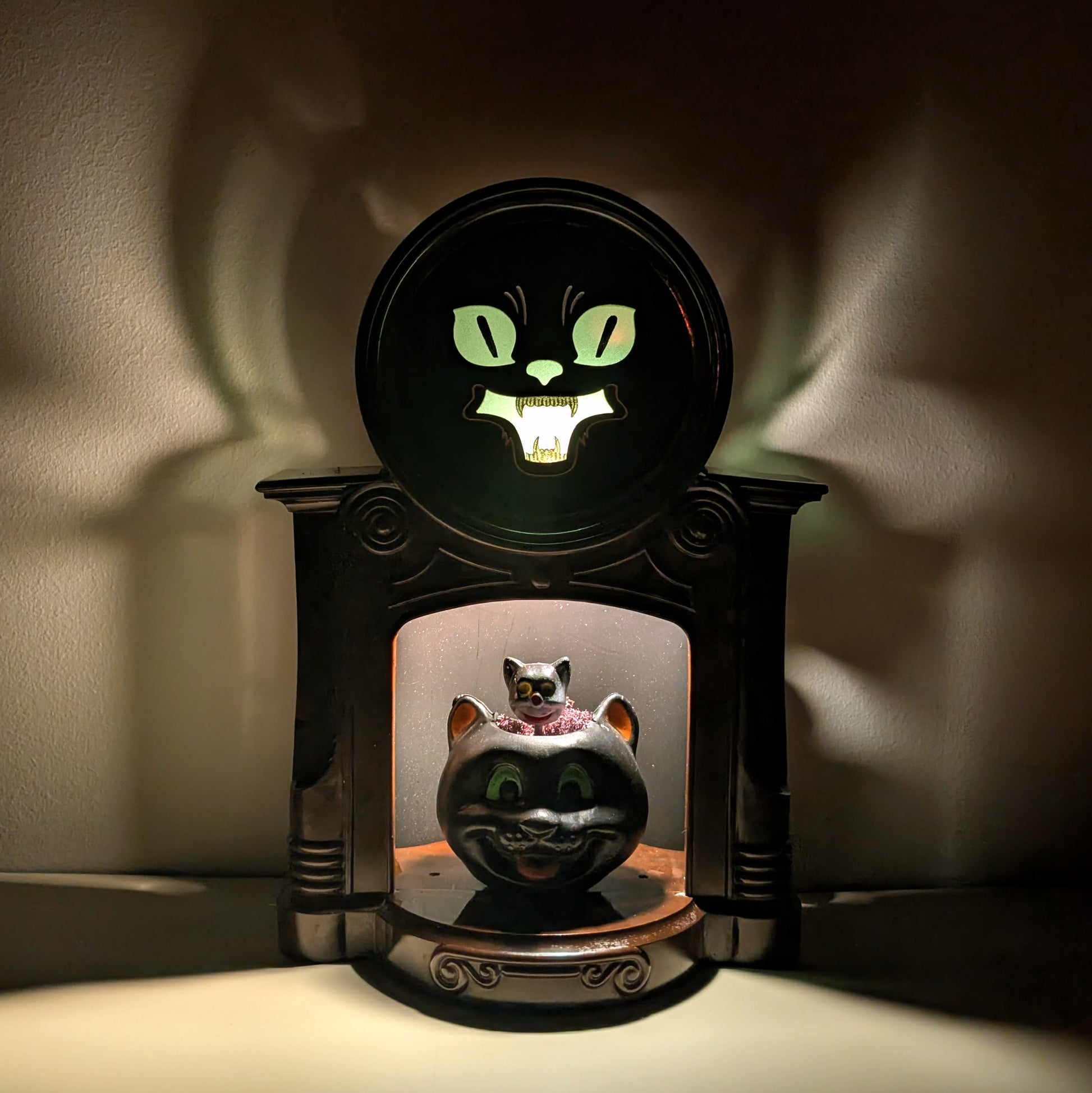 Decorative fireplace light with a vintage cat-themed design on a dark background