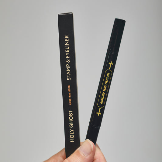 Hand holding a black makeup stamp and eyeliner package with visible branding against a neutral background