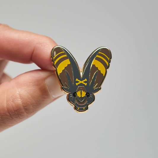 Enamel pin of a greater false vampire bat held by a hand against a neutral background