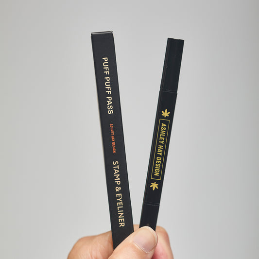 Two black cosmetic eyeliner stamps with 'Ashley Hay Design' branding on a neutral background