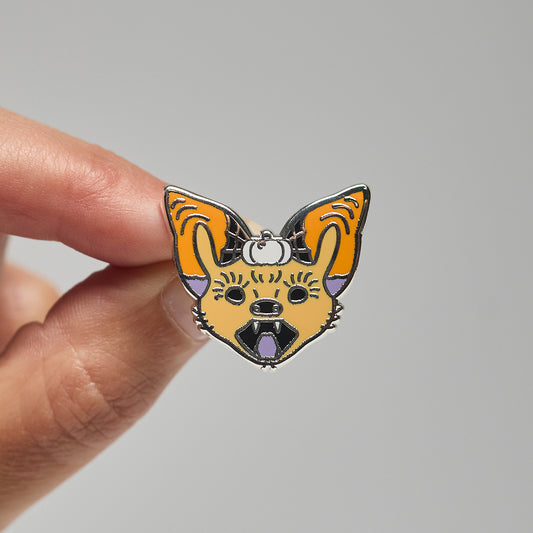 Enamel pin of a painted bat held by a hand against a neutral background