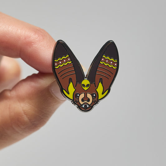 Enamel pin of a Rafinesque's big-eared bat held by a hand against a neutral background
