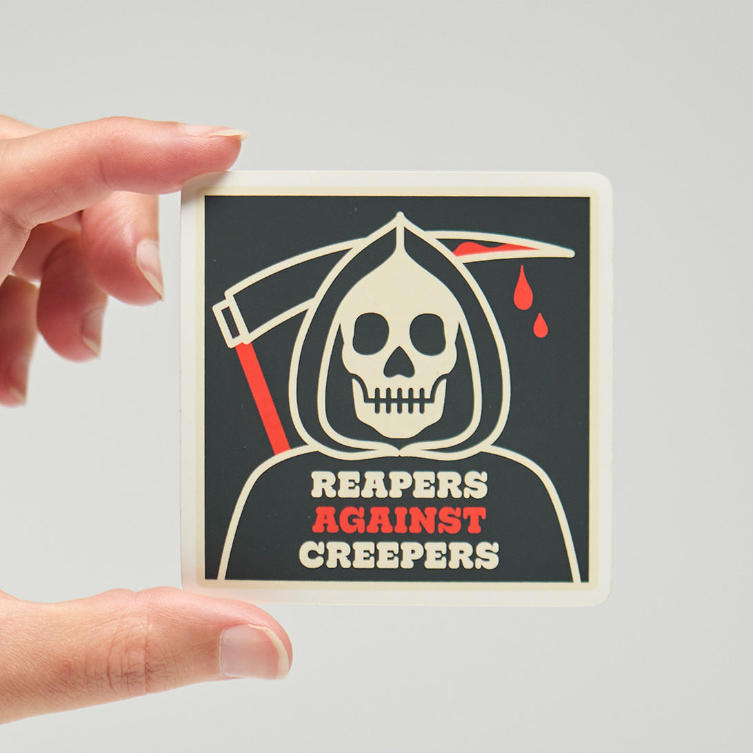 Sticker with a grim reaper design and text 'Reapers Against Creepers' held by a hand on a neutral background