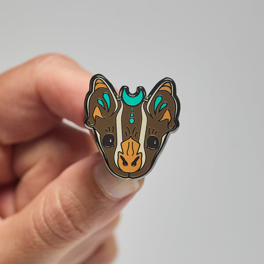 Enamel pin of a tent-making bat held by a hand against a neutral background