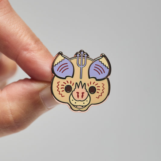 Enamel pin of a Pervical's trident bat held by a hand against a neutral background