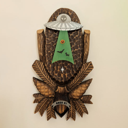 Wooden wall art with alien and UFO beaming up bats and a pumpkin design on a beige background