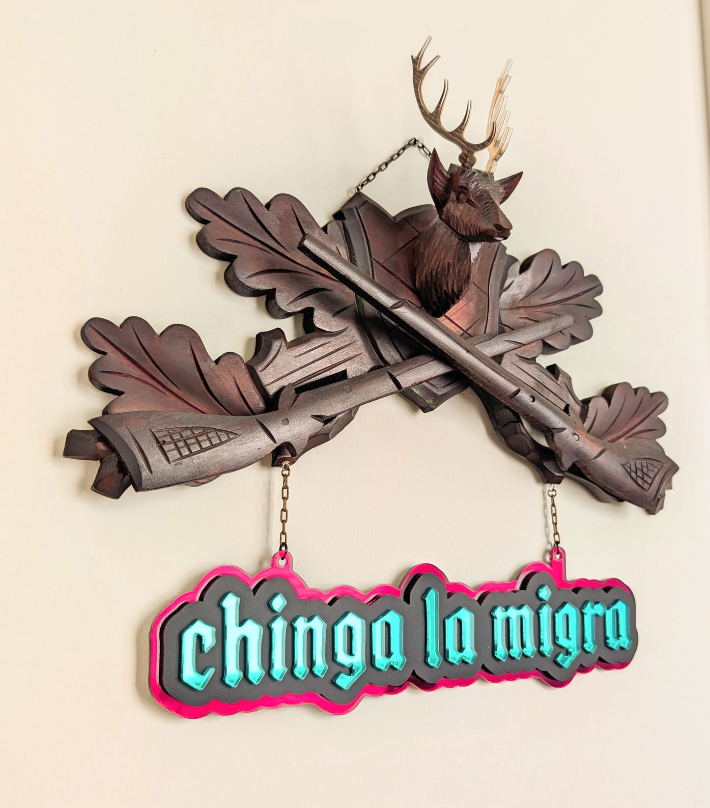Vintage deer and rifle cuckoo clock top with mirrored sign that reads "Chinga la Migra."