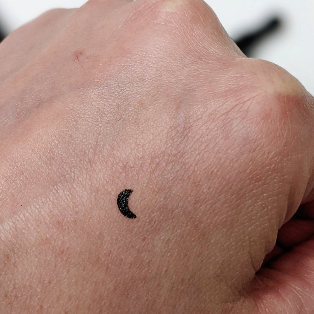 Black crescent moon makeup stamp on skin