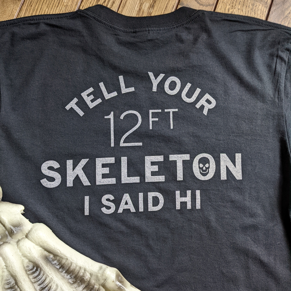 alt="Black shirt with the words Tell Your 12ft Foot Skeleton I said Hi"