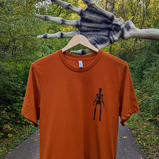 alt="Orange shirt with a skeleton printed on the corner front"