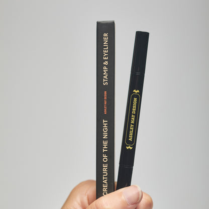 Hand holding a black makeup stamp and eyeliner package with visible branding against a neutral background