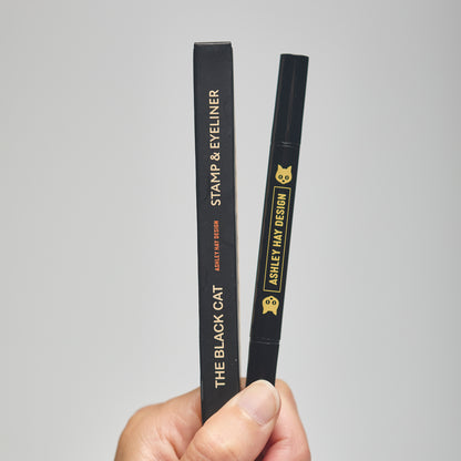 Hand holding a black makeup stamp and eyeliner package with visible branding against a neutral background