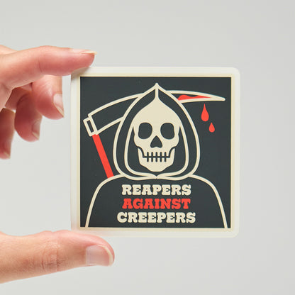 Sticker with a grim reaper design and text 'Reapers Against Creepers' held by a hand on a neutral background