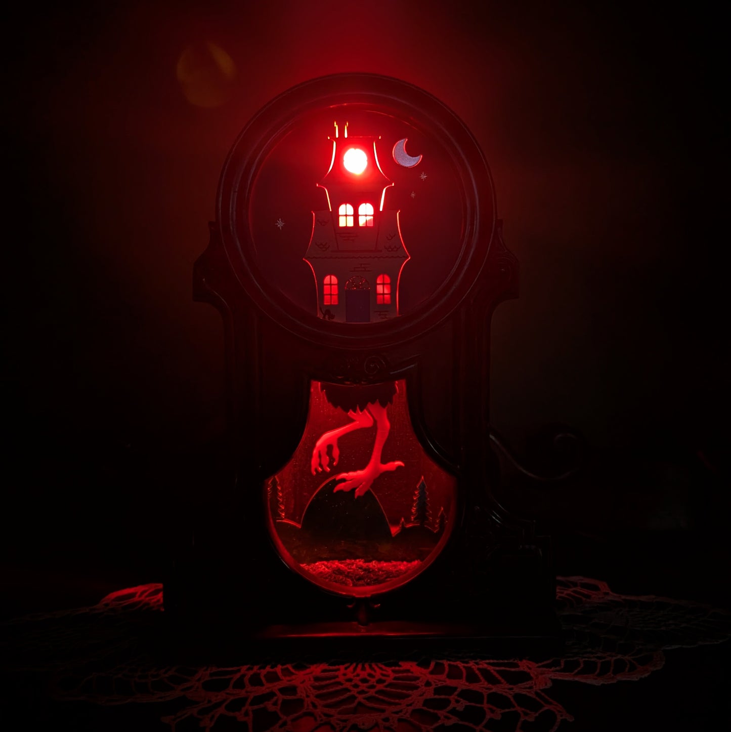 Decorative fireplace light with a Baba Yaga house design against a green background lit up with a red light.