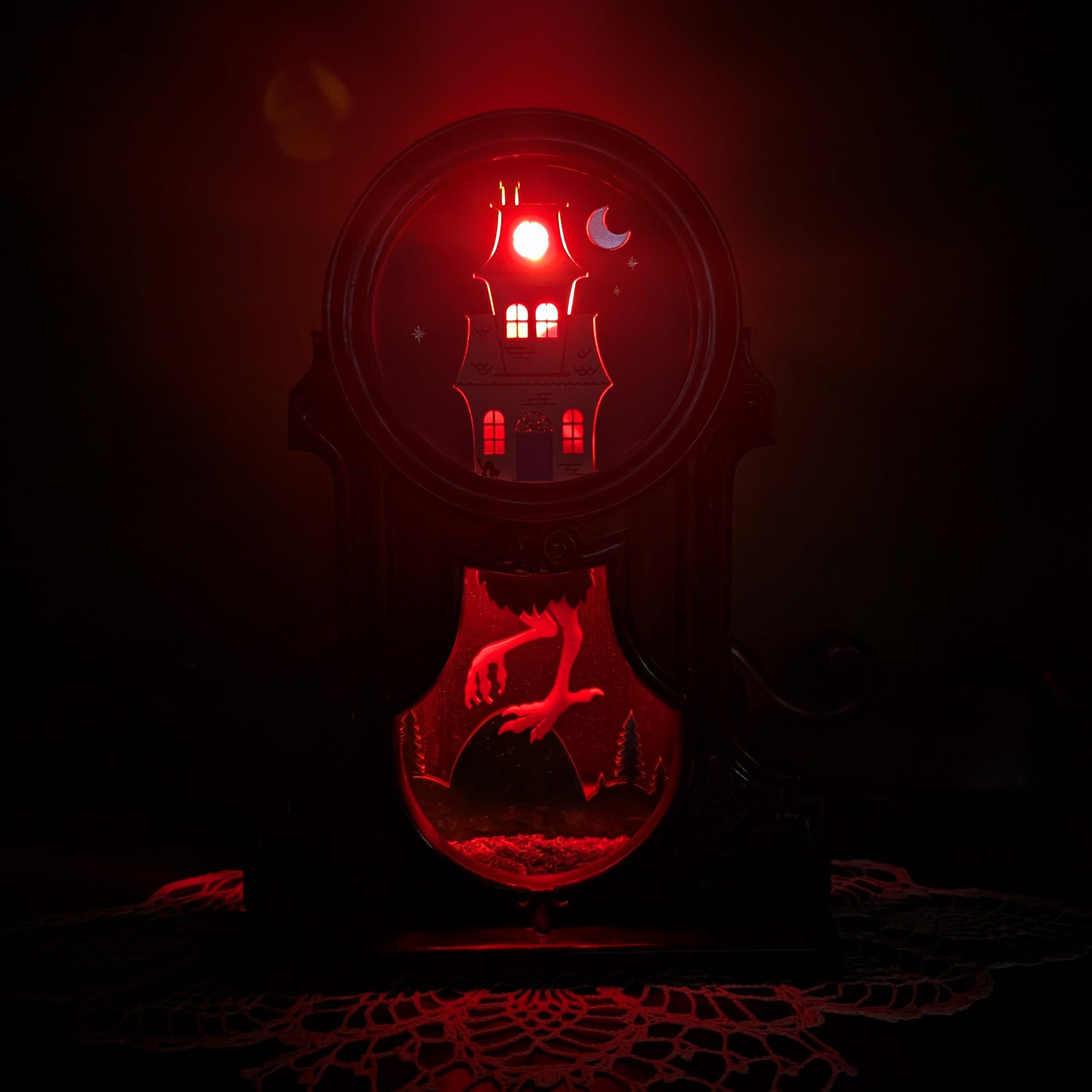 Decorative fireplace light with a Baba Yaga house design against a green background lit up with a red light.