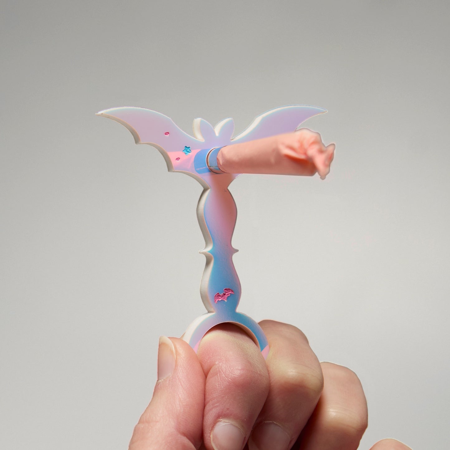 Handing holding a wand of an iridescent bat with a pre-roll inserted into the middle. 