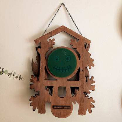 The back of a cuckoo clock frame with a jack-o-lantern face.