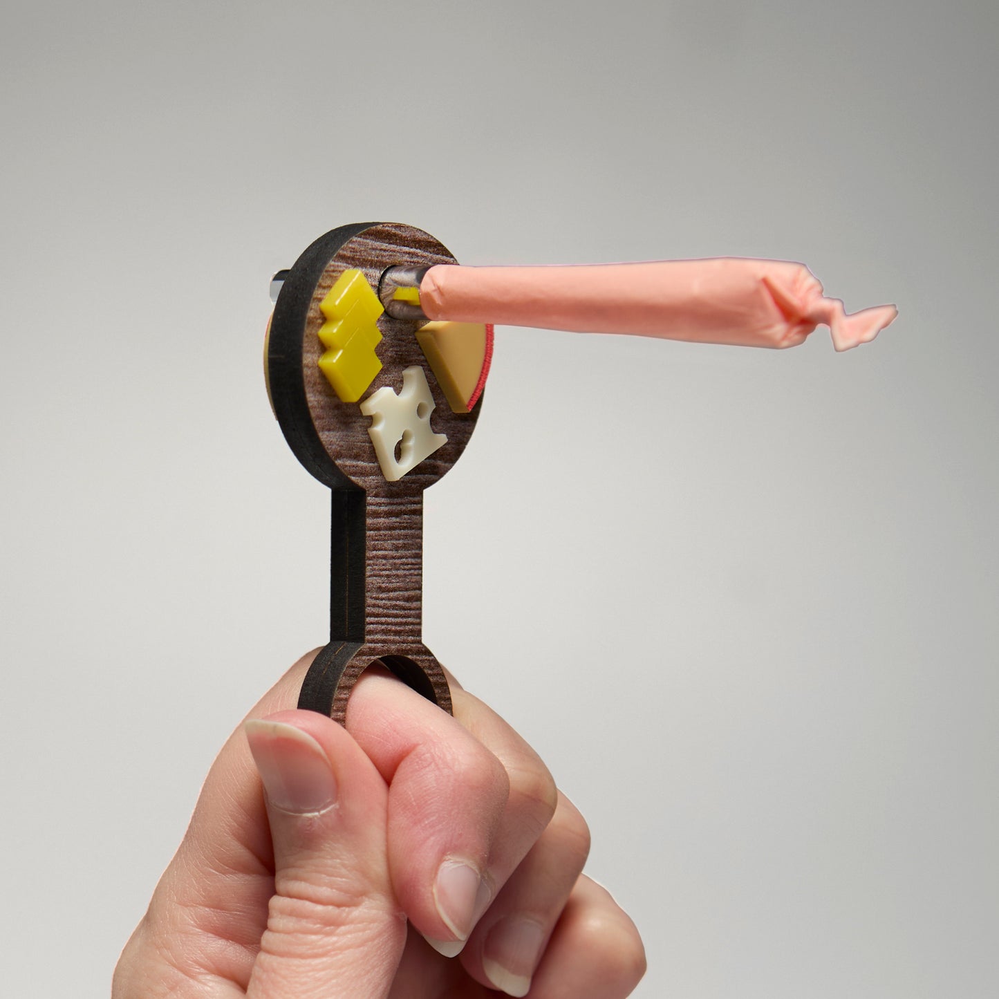 Handing holding a wand of a cheese board with a pre-roll inserted into the middle. 