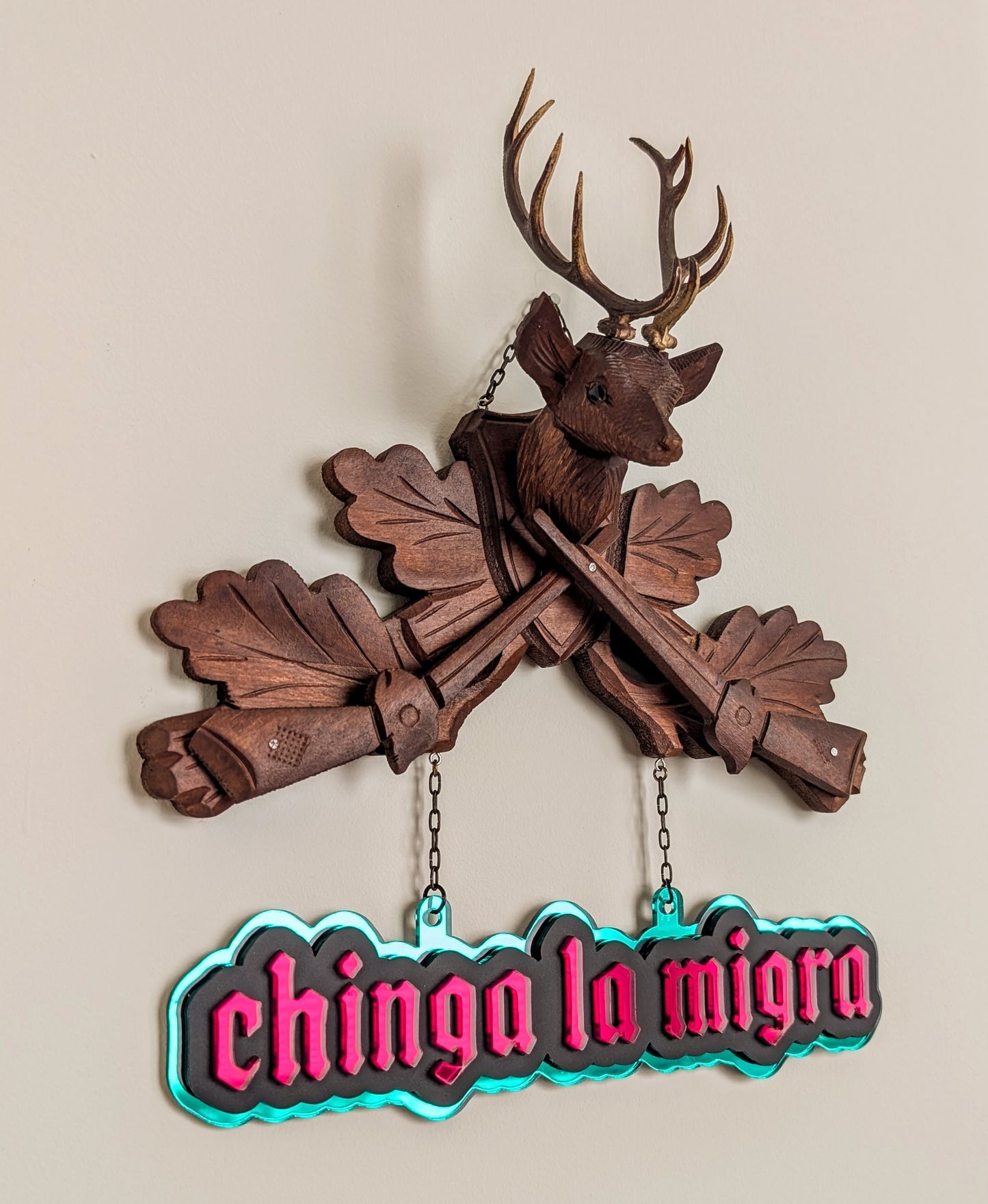 Vintage deer and rifle cuckoo clock top with mirrored sign that reads "Chinga la Migra."