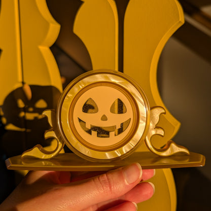 A vintage plastic clock frame repurposed with a yellow jack-o-lantern face. 