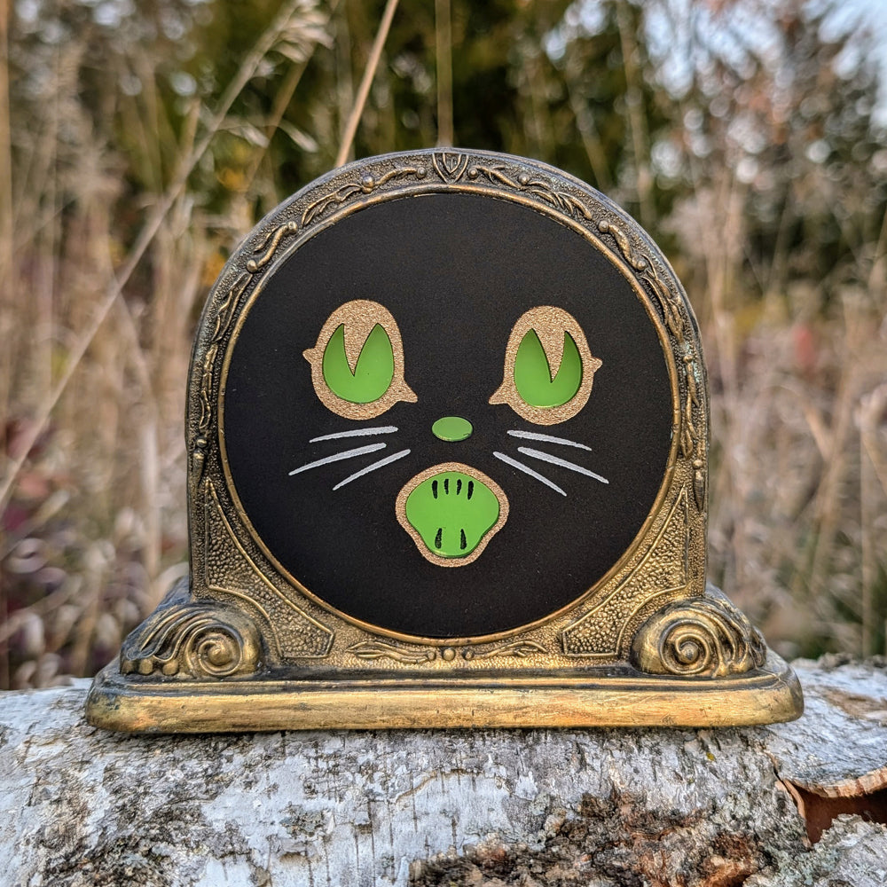 Repurposed vintage brass frame with a Biestle cat face outside