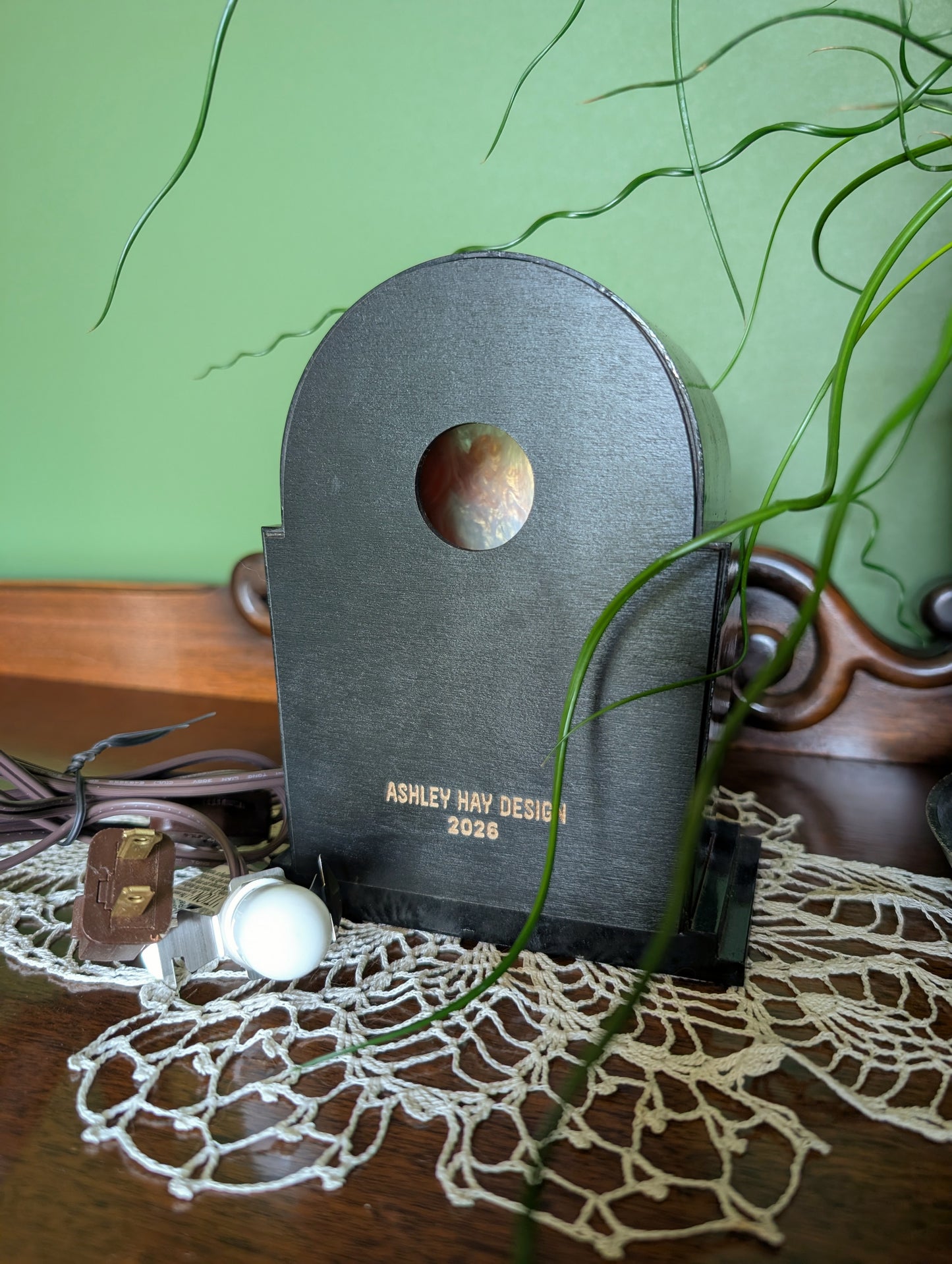 The back of the clock frame with a hole for the light bulb to sit in. It is engraved 'Ashley Hay Design 2026'