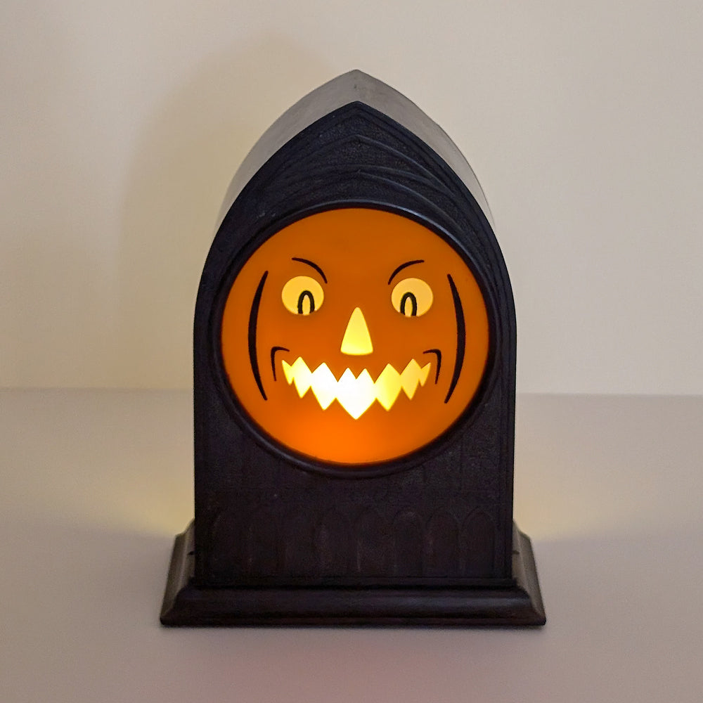 Vintage mantle clock of a Halloween face with an angry smirk lit up