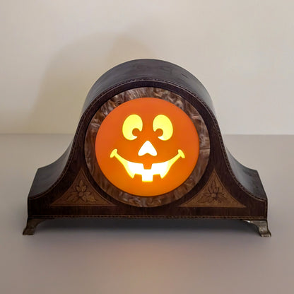 Vintage wood mantle clock with a jack-o-lantern smiling face lit up