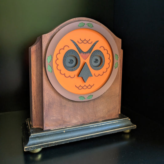 A vintage wood clock frame repurposed with an orange owl face based on a Halloween blow mould.