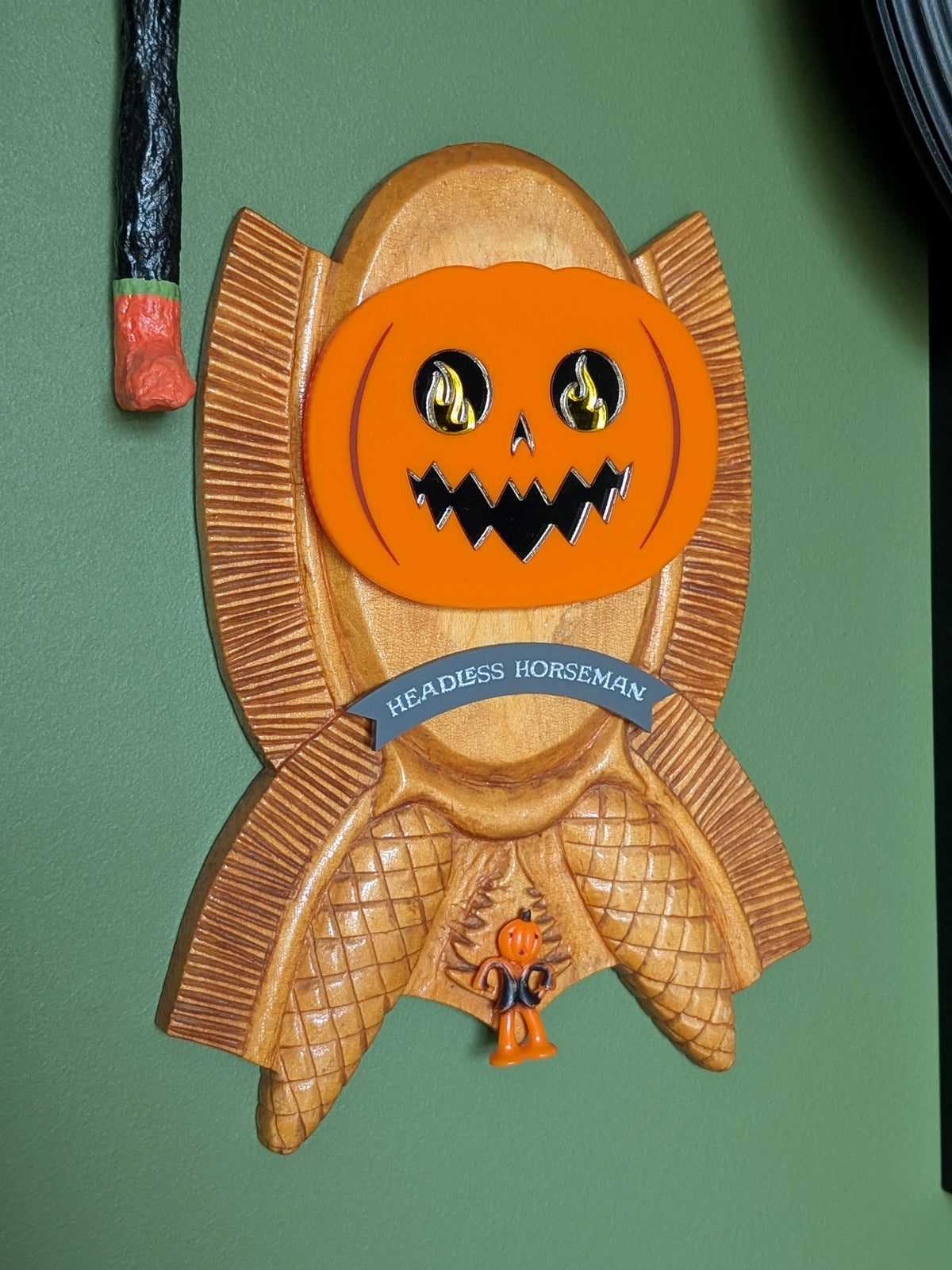A vintage wooden carved wall plaque featuring an acrylic Headless Horseman and a little pumpkin guy. A gray banner reads 'HEADLESS HORSEMAN' in the middle.