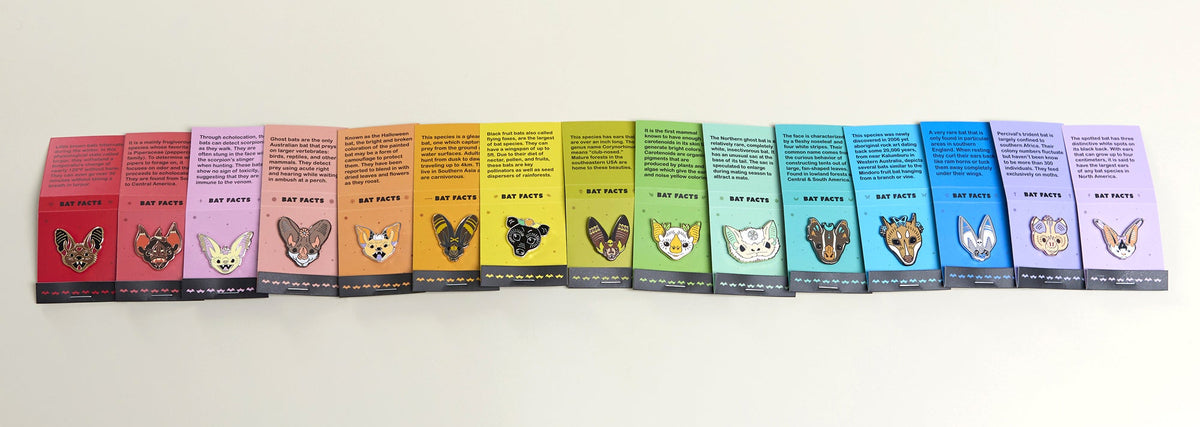 A row of bat pins in rainbow color order on a white background.