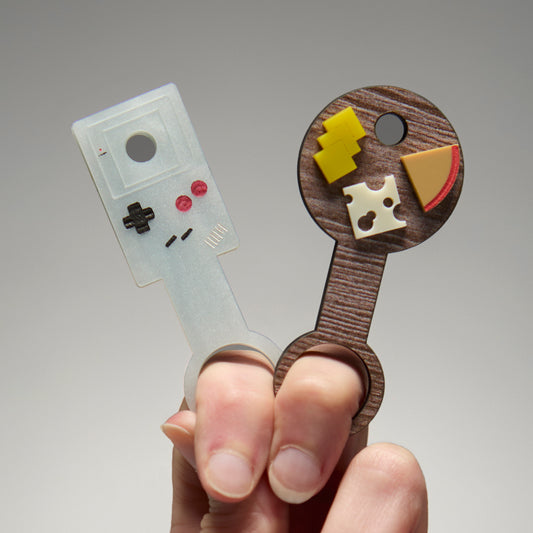 Handing holding two wands that hold pre-rolls. One is a cheeseboard and the other in a vintage Gameboy.